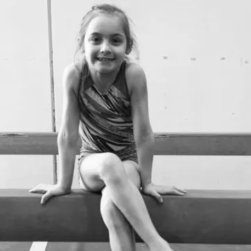 Olivia sitting on a balance beam
